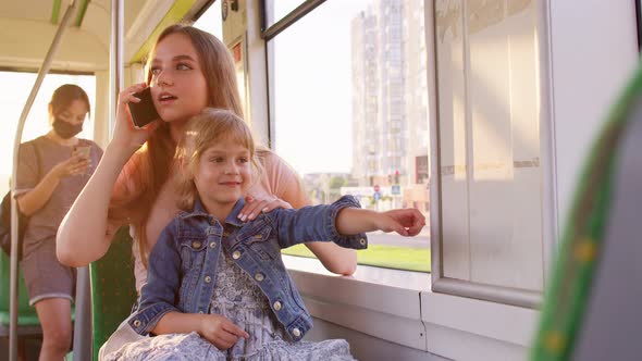 Young Family Woman with Kid Girl Sitting in Public Bus Transport Mother Talking on Mobile Phone alt
