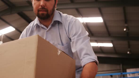 Male worker arranging box in warehouse alt