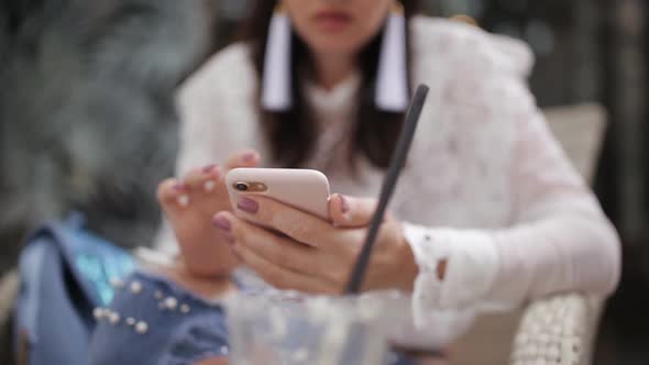 Girl in the Cafe Uses a Smartphone Closeup