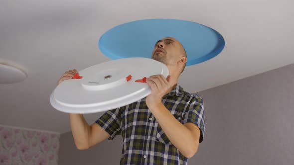A Man Installs a Modern Led Ceiling Light on the Ceiling alt