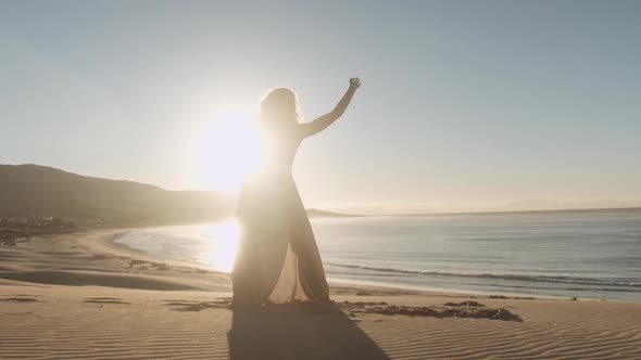 Dancer In Long Dress Performing On Sandy Beach alt