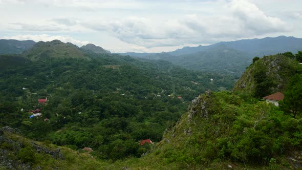 Green mountain cliffs overlooking a city in the valley of Tana Toraja in Sulawesi Indonesia. alt