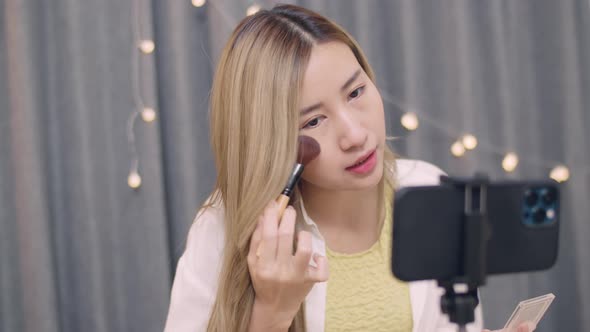 Young Asian female beauty blogger influencer makeup artist recording on smartphone educational.