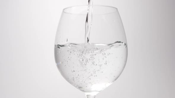 Water pour into a wine glass on a white background