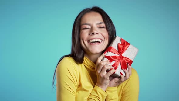 Pretty woman received gift box and interested in what's inside. She is happy and flattered alt