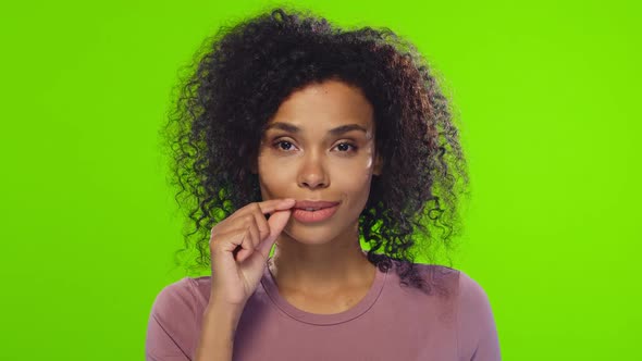 Dark-skinned young woman shows sign of silence, closes her mouth on the lock alt