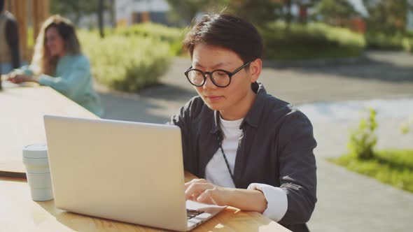Asian Female Freelancer Using Laptop in Park alt