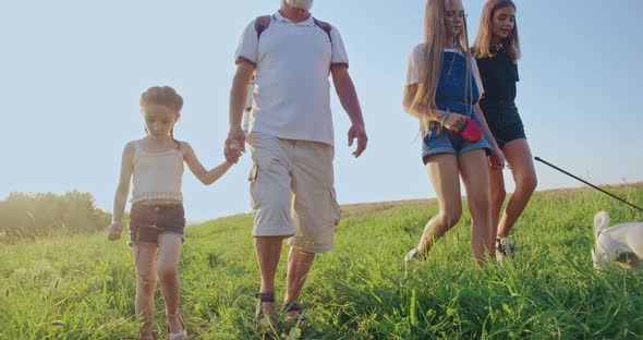Father with Daughters and Dog Walking Along Field in Countryside alt