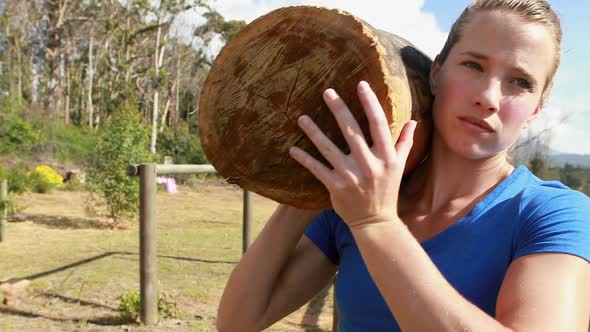 Fit woman carrying heavy wooden log alt