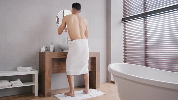 Full Length View Funny Cheerful Man with White Bath Towels Wrapped Around Hips Standing in Bathroom alt
