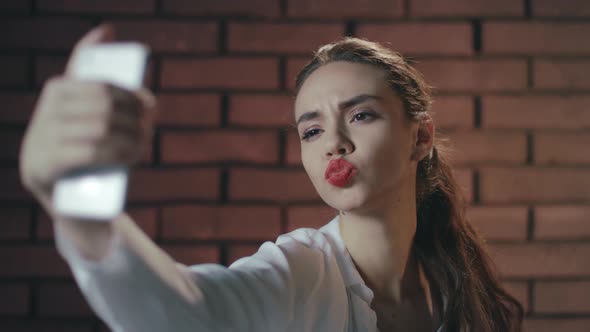 Sexy Woman Using Mobile Phone for Selfie Photo on Brick Wall Background alt