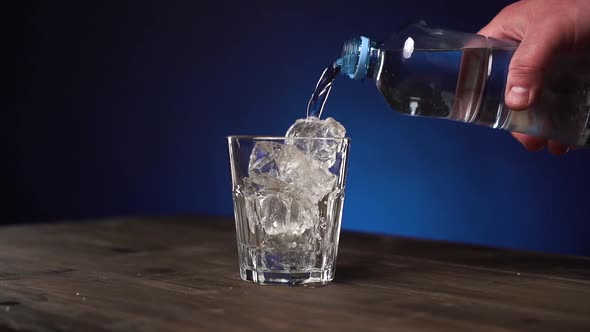 Transparent Clean Drinking Water Is Poured Into Glass with Crushed Ice. The Glass Is Spinning and alt