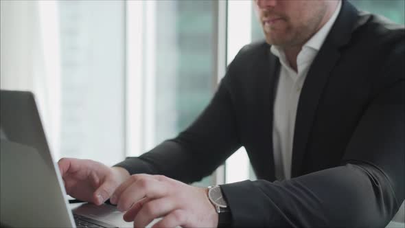 Young Businessman in His Office on the Background of a Skyscraper alt