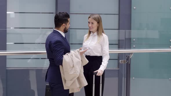 Businesswoman with rolling bag is met by business partner