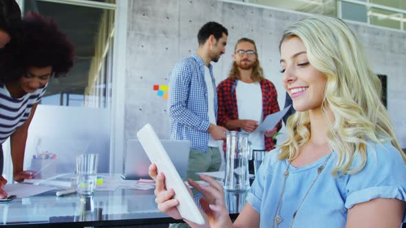 Woman using digital tablet with her colleagues in background alt