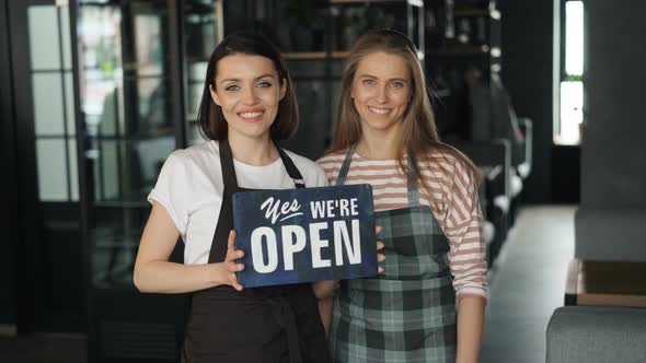 Portrait of Beautiful Business Owners Holding Open Sign in Cafe Smiling alt