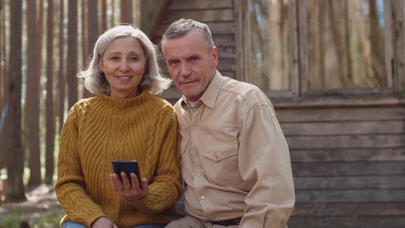 Portrait of Aged Couple near Wooden Country House alt