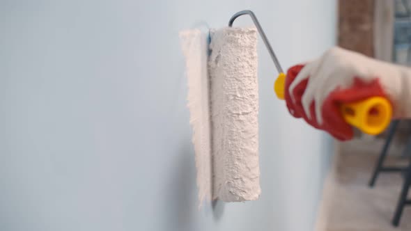 Close Up of Worker Hand in Gloves Painting Wall with Roller alt