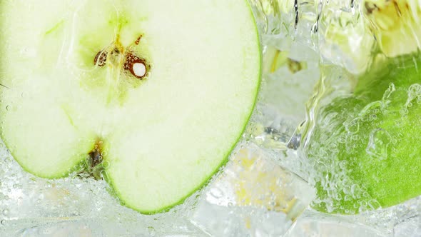 Super Slow Motion Shot of Pouring Water on Apple Slices and Ice Cubes in Glass at 1000 Fps alt