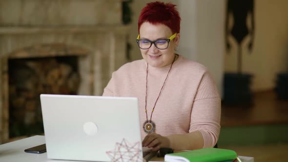 Middle Aged Business Woman Using Laptop at Home Enjoying Rubbing Her Hands