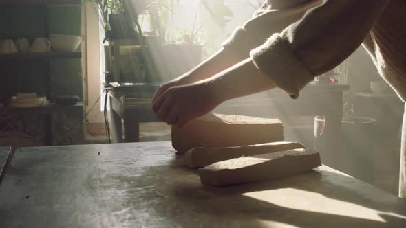 Woman Is Cutting Raw Clay Into Pieces alt