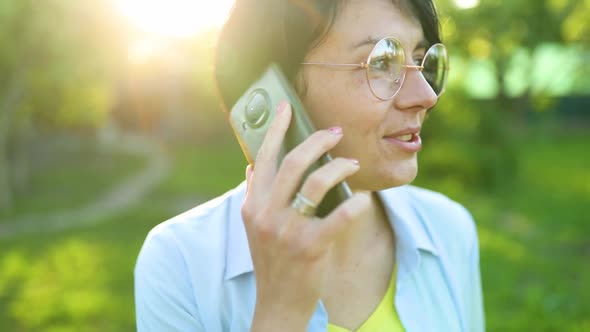 Happy woman in glasses talking on mobile phone outdoor