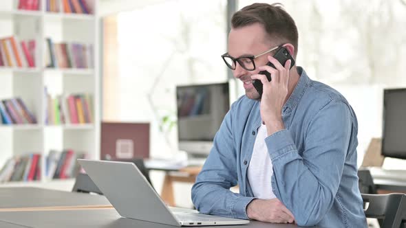 Young Man Talking on Smartphone in Office alt