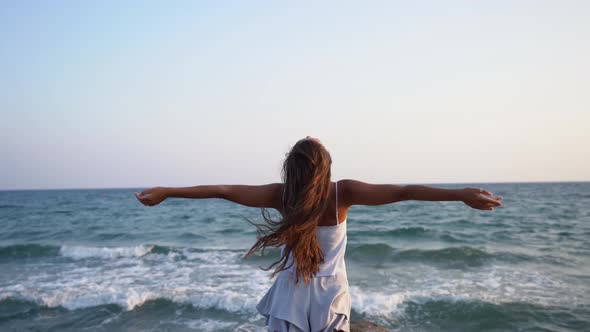 Woman Looking at Sea View with Arms Outstretched in Summer