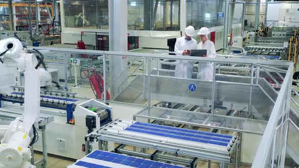 Factory Unit with Two Specialists and a Robot Relocating Solar Panels alt