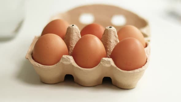 Organic Chicken Eggs in a Brown Paper Box Placed on White Table