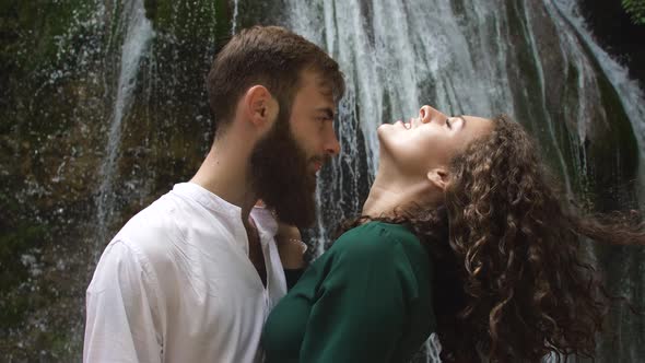 Sexy Young Woman with Curly Blond Hair in the Arms of a Young Man with a Beard on the Background of alt