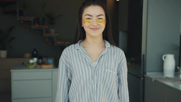 Slow Motion Portrait of Smiling Asian Woman with Eye Patches Standing in Kitchen at Home alt