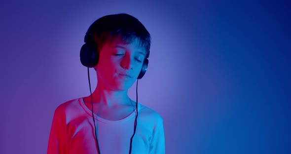 Young Boy With Headphones Listening to Music in Neon Lights