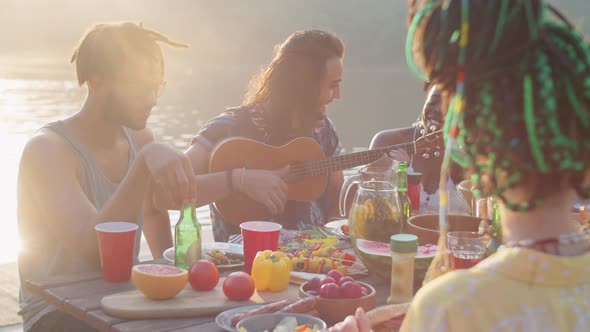 Happy Friends Playing Ukulele and Singing at Lake Party alt