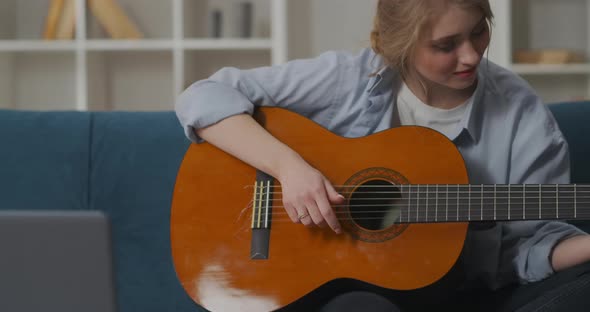 Young Female Beginner Musician Is Playing Guitar and Shaking Her Head To Beat Smiling Woman in