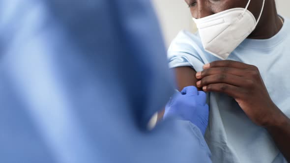 Female doctor preparing to vaccinate black male patient alt