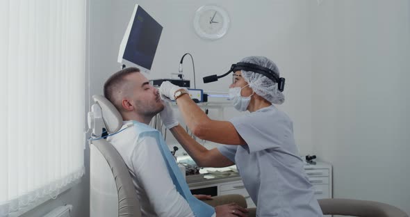 A Otorhinolaryngologist Examines the Sinuses of a Patient Using a Medical Mirror alt