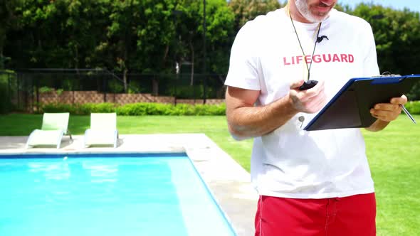 Lifeguard holding clipboard and looking at stop watch alt