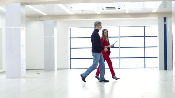 Businessman Walks Through Rented Office Space and Talks to Female Real Estate Agent Side View alt