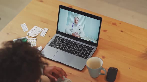 Young African Female in Selfisolation Communicates with a Doctor By Video Call Using a Laptop a alt
