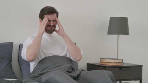 Young Man Having Headache While Sleeping in Bed alt