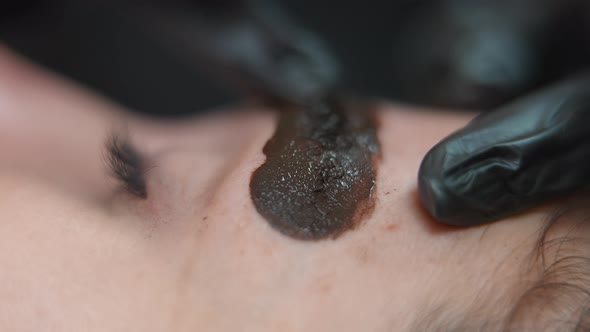 Finger in Gloves Spreading Ink on Eyebrow Skin of Client in Beauty Salon alt