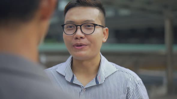 Asian businessman have a conversation with an employee standing in the urban city.