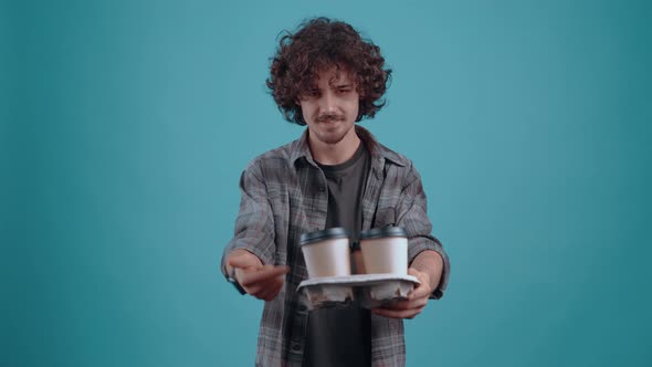 The Cheerful Student Hands Out 4 Glasses of Coffee From Which He Proposes to a Friend to Take One alt