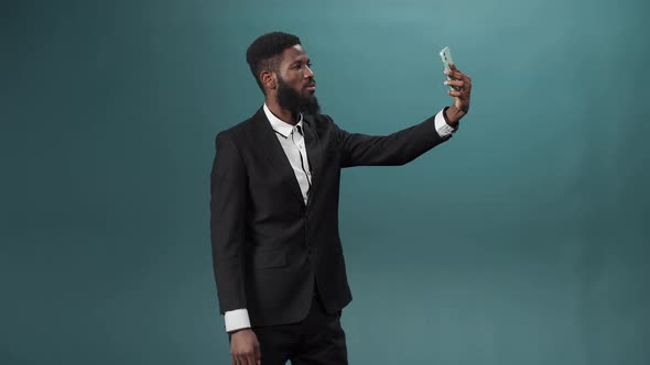 A Pretty African Man with a Dark Beard in a White Shirt and Black Suit is Taking Some Photos on His alt