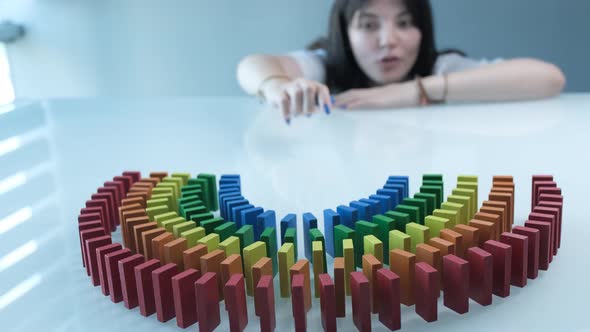 Line up of Dominoes in Rainbow Falling Colors with LGBT Colors of a Hand alt