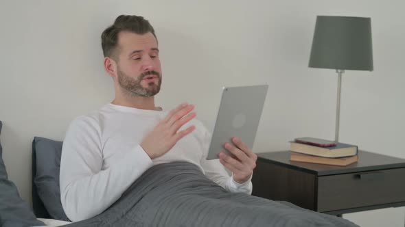 Man Doing Video Call on Tablet in Bed alt