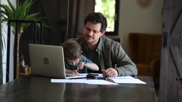 Father is trying to work and play with a little boy at same time at home.