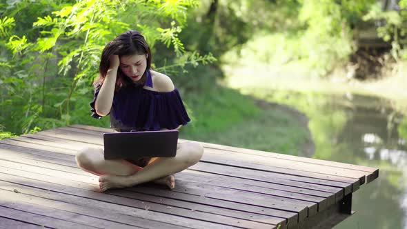 stressed woman using laptop computer on a wooden jetty