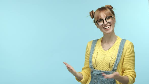Cute Young Woman in Glasses and Yellow Sweater Introduce you to Promo Offer Pointing Hands Left and